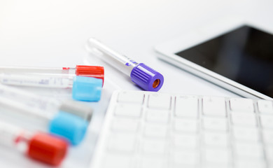 Medicine bottles for samples next to computer tablet and computer keyboard in medicine, closeup on white background