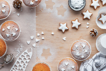 Top view of the table with sugar-sprinkled muffins, fondant icing and Christmas star cookies