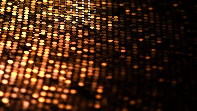 Golden metallic glitter fabric surface rotation. Holiday abstract glitter background with blinking lights. Sequin backdrop. Slow motion. 4K UHD video footage. 3840X2160