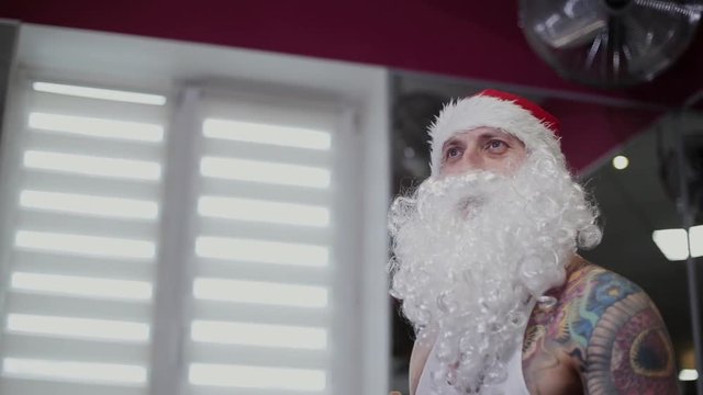 Fitness instructor Santa Claus in the gym drinks water from a shaker and gets angry.