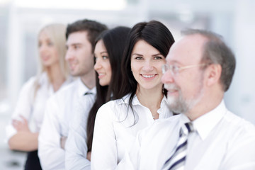Close-up portrait of executive business people standing in a row at office and looking at the camera.