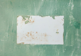 A photograph of weathered green paint on metal with white brush stokes and rust in a horizontal presentation