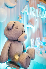 Baby-boy birthday party decor. White and blue balloons, lights and large Teddy-bear decorate restaurant hall ready for festive dinner