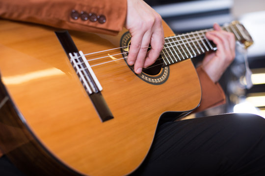 man in jacket playing an acoustic guitar