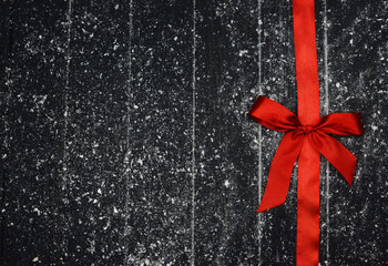 red bow tied with a ribbon textile on a wooden background
