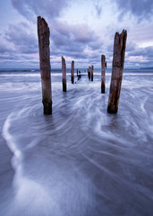Scenic view of wooden poles on a beach, the movement of the waves is shown in addition to a colorful evening sky - Location: Baltic Sea, Rügen Island