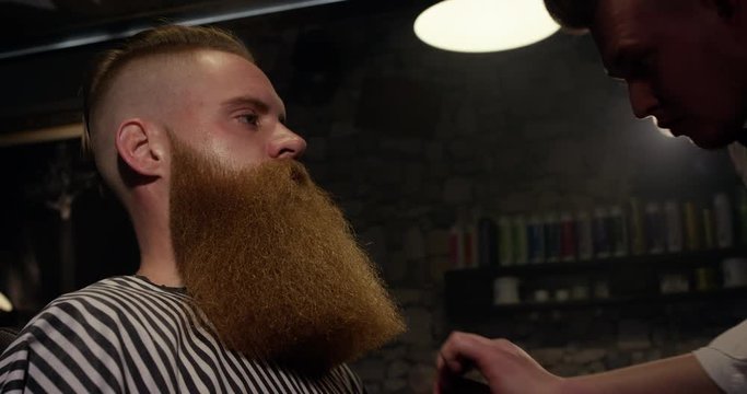 Barber with comb long beard male client in Barbershop slow motion