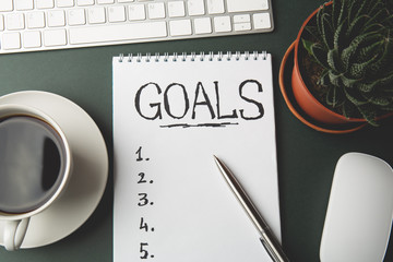Top view of GOALS list on notepad on dark table, business success inspiration and motivation concept