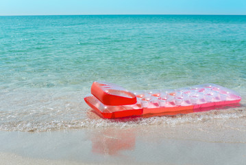 Beautiful pink air mattress lies in the blue sea water.