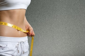 Slim young woman measuring her thin waist