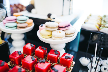 Festive candy bar serving. Macaroons, cupcakes, cookies, chocolates, eclairs and layered cake stand on the dinner table