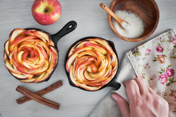 Homemade puff pastry with rose shaped apple slices baked in iron skillets