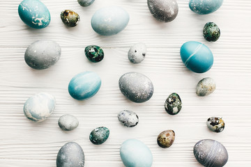 Stylish easter eggs on white wooden background, flat lay. Modern easter eggs painted with natural dye in blue and grey marble color. Happy Easter pattern, greeting card