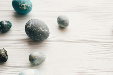 Stylish easter eggs on white wooden background with space for text. Modern easter eggs painted with natural dye in grey marble color. Happy Easter, greeting card