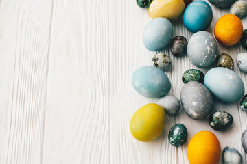 Stylish easter eggs on white wooden background with space for text. Modern easter eggs painted with natural dye in blue, grey, yellow marble color. Happy Easter pattern, greeting card
