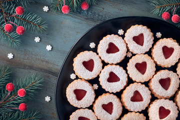 Top view of traditional Linzer cookies with red jam heart on dark background