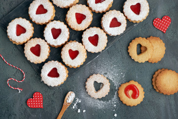 Top view of traditional Linzer cookies with red jam heart on dark background