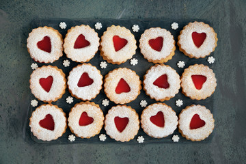 Top view of traditional Christmas Linzer cookies with red jam on dark