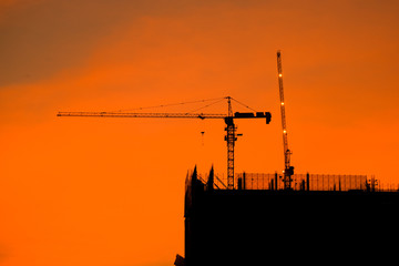 Crane building construction site at sunset or sunrise. High-quality stock photo image silhouette of construction tower crane in sunset sky background. Building construction with crane during sunset