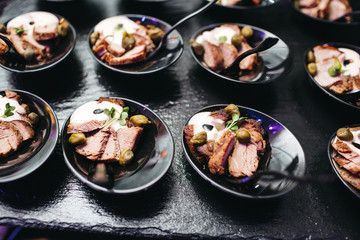 Beautifully decorated catering banquet table with profiteroles, salads and cold snacks. Variety of tasty delicious snacks on the table. Wedding table serving. Meat and vegetables