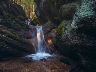 Fototapeta na wymiar Mountain creek waterfall among mossy rocks of the Seven Stairs Canyon in the Piatra Mare Mountain, Timisul de Jos, Brasov county, Transylvania region, Romania.