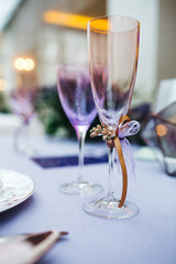 Dinner table serving. Violet and beige tones, pastel colors. Beautiful decoration of wedding banquet in restaurant with glasses, plates, forks and knives, white tablecloth.