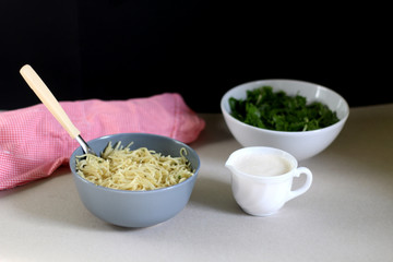 Bowls of lemony pasta, spinach and yoghurt sauce. Selective focus. 