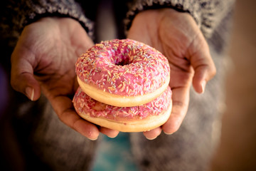 Closeup with pair of pink donuts not sugar free enemy of a healthy lifestyle and tasty junk food...