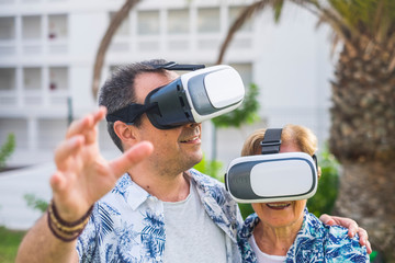technology concept for no young people middle age and mature man and woman enjoying the outdoor leisure activity with virtual realituy 3d playful lifestyle together laughing and smiling