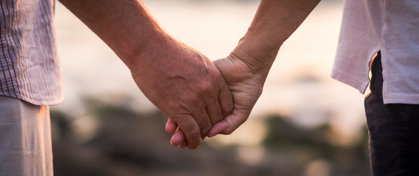 valentine's day love over time concept with hands of man and woman mature old people aged taking together each other with defocused background - romance and romantic picture for retired life