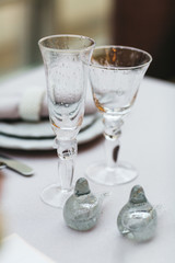 Dinner table serving. Violet and beige tones, pastel colors. Beautiful decoration of wedding banquet in restaurant with glasses, plates, forks and knives, white tablecloth.