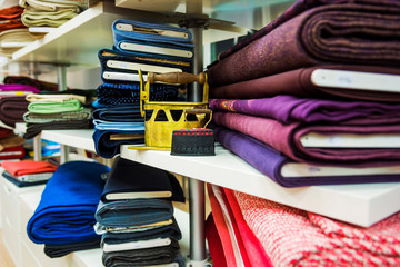 atelier tailoring. on the white shelves are multi-colored rolls of cloth. multi-colored decorative irons.