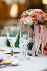 Dinner table serving. Violet and beige tones, pastel colors. Beautiful decoration of wedding banquet in restaurant with glasses, plates, forks and knives, white tablecloth.