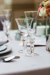 Dinner table serving. Violet and beige tones, pastel colors. Beautiful decoration of wedding banquet in restaurant with glasses, plates, forks and knives, white tablecloth.