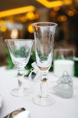 Dinner table serving. Violet and beige tones, pastel colors. Beautiful decoration of wedding banquet in restaurant with glasses, plates, forks and knives, white tablecloth.