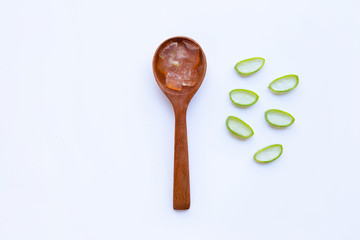 Aloe vera gel on wooden spoon with aloe vera slices on white background.