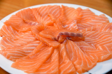 Slided Raw Salmon in white dish on wood blackground