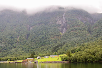 Obraz premium Main view of Styvi village and its farm museum with surrounding waterfalls on background. This tinny village is located on the western shore of the Nærøyfjord, north of Gudvangen village, Norway.