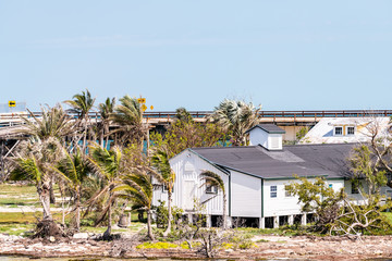 Many damaged, destroyed elevated, raised piling stilt houses on beach by shore, coast in Florida...