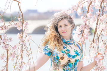 Young woman standing between, under cherry blossom, sakura flowers, branches, tree with Potomac...