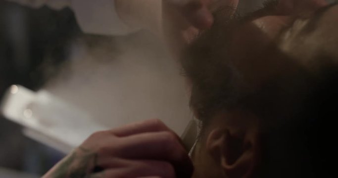 Barber cutting client beard with straight razor in Barbershop slow motion