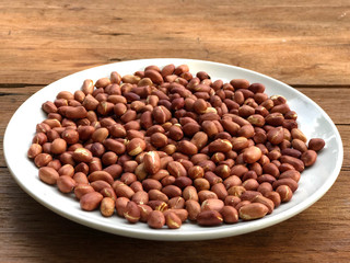 Closed up peeled peanuts in white dish on wooden table with natural light , ingredients of peanut butter. Healthy food.top view and copy space.