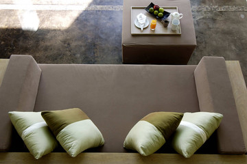Top view of a brown leather couch and pillows in a living room.