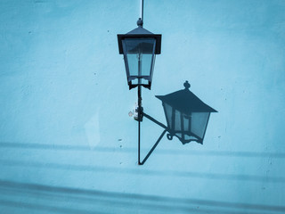 Colonial street lamp casting shadow on a blue wall in Trinidad Cuba