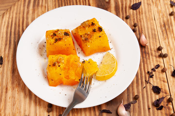 Baked pumpkin with garlic, rosemary and spices on a plate on the table. Appetizer. Garnish. Vegetarian food