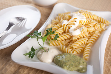 Pasta in white plate, parsley, bowl with mayonnaise sauce