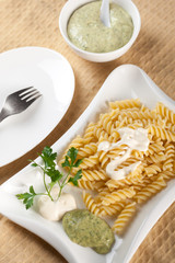 Pasta in white plate, parsley, bowl with mayonnaise sauce