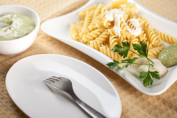 Pasta in white plate, parsley, bowl with mayonnaise sauce
