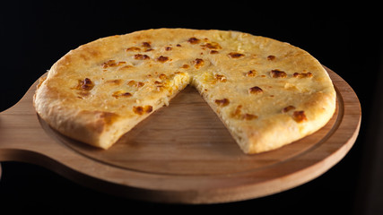 Georgian traditional food khachapuri on the wooden dish on black background