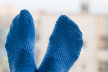 Woman legs in blue socks on a blurred window light background.